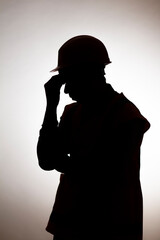 Wall Mural - silhouette of tired builder bowed head in emotional stress on depressive isolated background, male unemployment concept