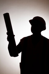 Wall Mural - silhouette figure of young construction worker in hard hat on isolated background showing with paper scroll direction forward, work managing