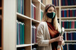 © Drazen - Portrait of happy student with face mask at college library.