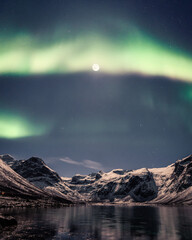 Poster - Vertical shot of a night winter landscape with the moon and Northern lights reflection on the river