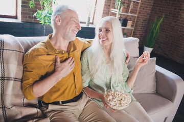 Sticker - Photo of old impressed funny grandmother grandfather sitting sofa laughing eating pop corn watching comedy indoors flat home house