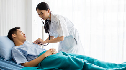 a pretty young doctor checking heart pressure by using stethoscope with patient man who sleep on blu