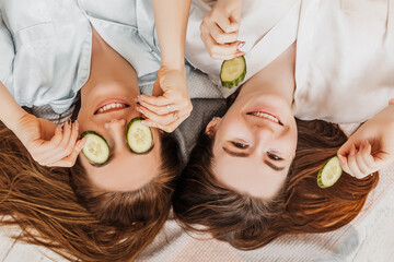 Wall Mural - two girls make homemade face and hair beauty masks. cucumbers for the freshness of the skin around t