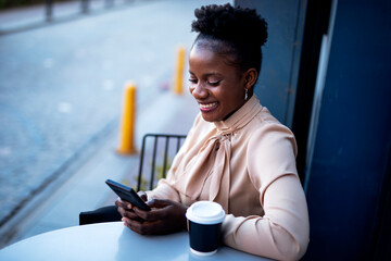 Businesswoman using the phone in cafe. African woman with laptop in coffee shop