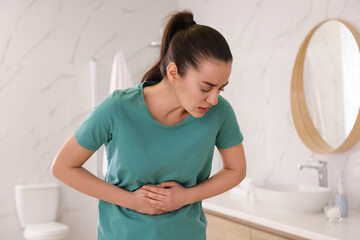 Wall Mural - Young woman suffering from stomach ache in bathroom. Food poisoning