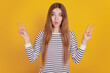Portrait of positive lady fooling around grimacing showing v-sign on yellow background