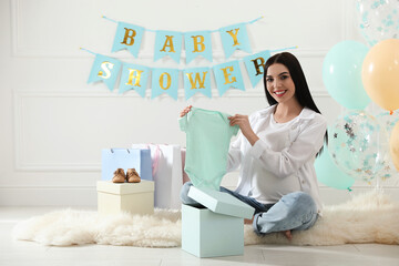 Sticker - Happy pregnant woman holding onesie in room decorated for baby shower party