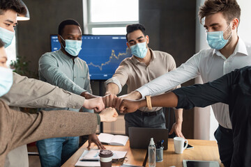 Wall Mural - Portrait of diverse business people in masks giving fist bump