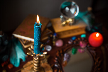 A fortune teller, witch stuff on a table, candles and fortune-telling objects. The concept of divination, astrology and esotericism