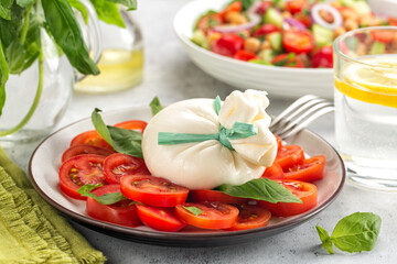 Poster - Italian summer dinner. Close-up of  burrata cheese on tomatoes and basil leaves.