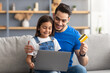 © Prostock-studio - Family using computer and credit card at home