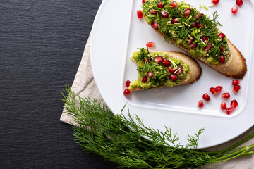 there are two healthy snacks on the grater of avocado, pomegranate and dill, one of which is bitten