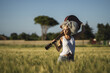 Curly-haired Spanish cute woman posing in a wheat field with an acoustic guitar