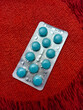 cyan pills in a pharmaceutical blister pack on a red cloth background