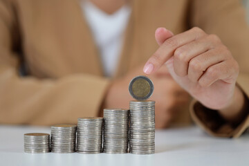 Smart and active asian businesswoman hands holding on stacking coin growing on white table and white background, meaning of earning money or investment or tax for business advertising concept