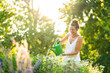 © Annika List/Westend61 - Young woman watering flowers in springtime garden