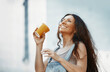 © Arman Zhenikeyev/Westend61 - Cheerful woman drinking coffee from disposable coffee cup in city