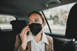 © David Molina Grande/Westend61 - Businesswoman wearing protective face mask talking on smart phone while traveling in taxi