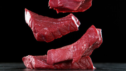 Wall Mural - Raw beef steaks falling on stone table