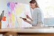 © Emma Innocenti/Westend61 - Young woman holding color palette while painting abstract canvas at home studio