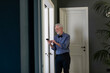 © Emma Innocenti/Westend61 - Senior man using phone while standing by window at home