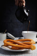 © Ignacio Ferr√°ndiz Roig/Westend61 - Plate of churros with hand of man pouring hot chocolate in background