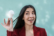 © COROIMAGE/Westend61 - Surprised businesswoman holding light bulb against turquoise wall