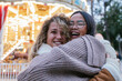 © Julio Rodriguez/Westend61 - Laughing female friends embracing against illuminated carousel
