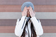 © Julio Rodriguez/Westend61 - Teenage girl covering her face with hands while standing against wall