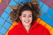 © Julio Rodriguez/Westend61 - Woman smiling while lying on back at footpath