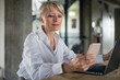 © Robijn Page/Westend61 - Blond businesswoman with laptop using mobile phone while sitting at desk in home office