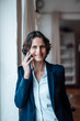 © Robijn Page/Westend61 - Smiling businesswoman talking on smart phone at home