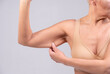 © OneInchPunch/Westend61 - Woman pulling muscle skin while standing against gray background