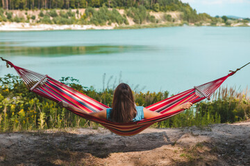 Wall Mural - woman laying on hammock enjoying the view of summer lake