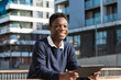 © NOVELLIMAGE/Westend61 - Smiling young man with digital tablet leaning on railing against building during sunny day