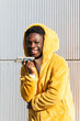 © NOVELLIMAGE/Westend61 - Smiling young man wearing yellow jacket talking on smart phone against white wall
