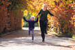© Petra Silie/Westend61 - Mother and daughter holding hands and running in park during autumn