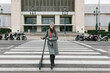 © Xavier Lorenzo/Westend61 - Smiling woman with electric push scooter crossing road in city