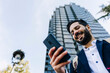 © Xavier Lorenzo/Westend61 - Smiling businessman using smart phone while standing in city