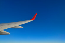 Wing Of Commercial Airplane Flying Against Clear Blue Sky