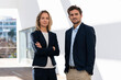 © steve brookland/Westend61 - Confident businesswoman with arms crossed standing by colleague against white wall
