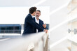 © steve brookland/Westend61 - Mature businessman smiling while talking with colleague standing at office building terrace