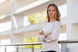 © steve brookland/Westend61 - Smiling businesswoman with arms crossed standing by railing at office terrace