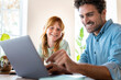 © steve brookland/Westend61 - Smiling redhead girl with father looking at laptop in living room