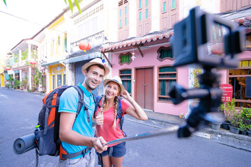 Wall Mural - Tourism and technology. Traveling backpacker couple taking selfie on action camera together outdoors.