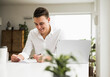 © Uwe Umst√§tter/Westend61 - Happy young businessman reading document while sitting in home office