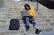 © Veam/Westend61 - Smiling man with leg prosthesis using laptop while sitting on steps