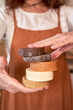 © Veam/Westend61 - Woman holding pile of handmade soaps at workshop