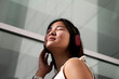 © Veam/Westend61 - Asian woman listening music through headphones outdoors