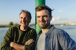 © Gustafsson/Westend61 - Smiling father and son by pole against river on sunny day